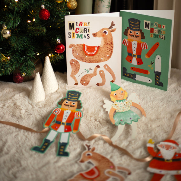Christmas-themed greeting cards with decorative puppets on a soft surface.
