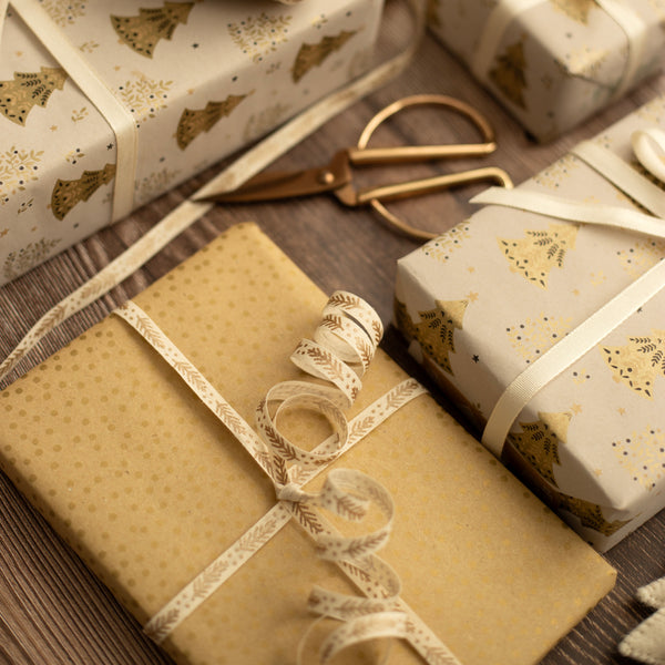 Gift boxes wrapped in brown and patterned paper with ribbons on a wooden surface.