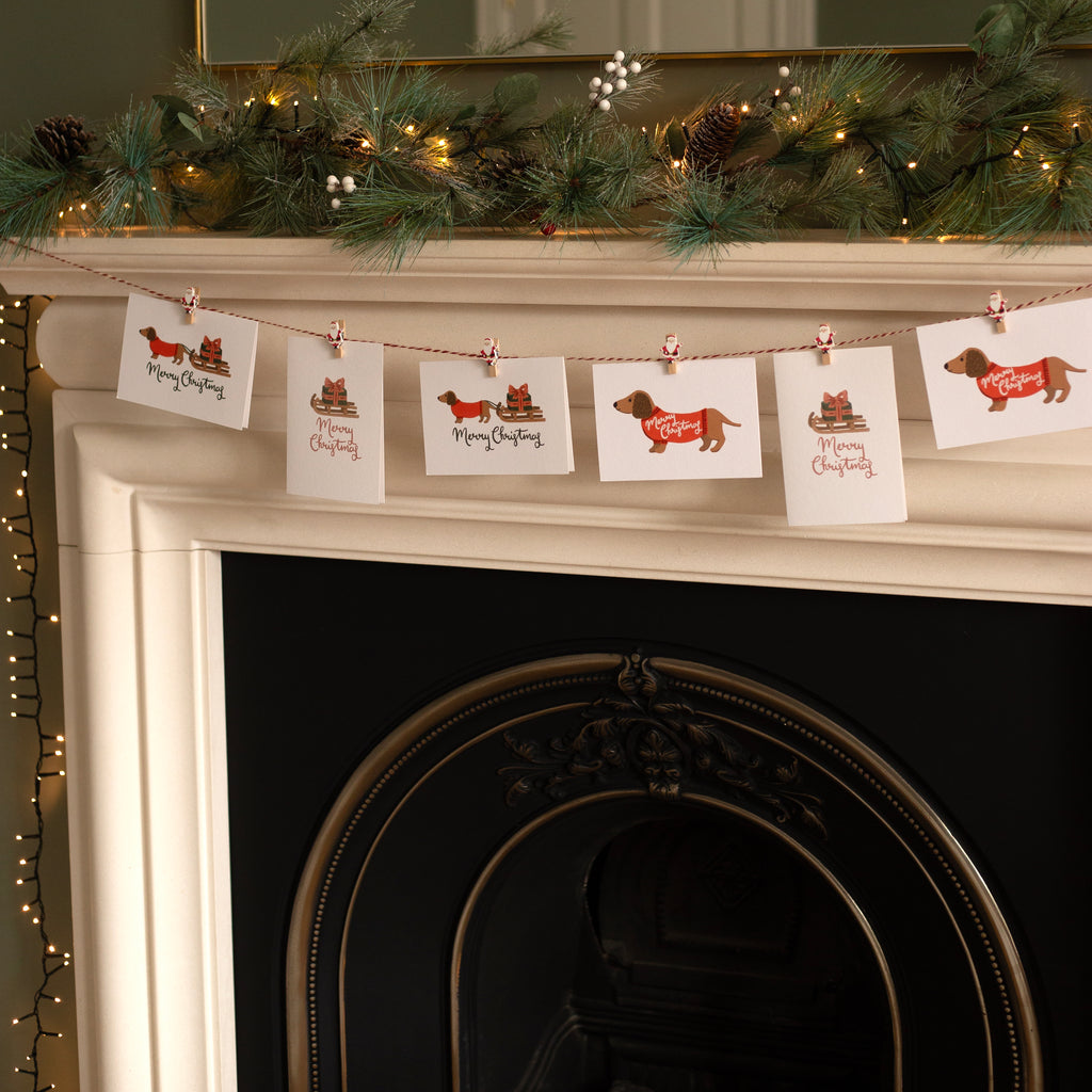 Decorative Christmas cards with dogs hanging on a fireplace mantel.