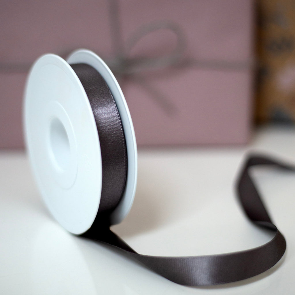 close up of grey ribbon in front of a pink present