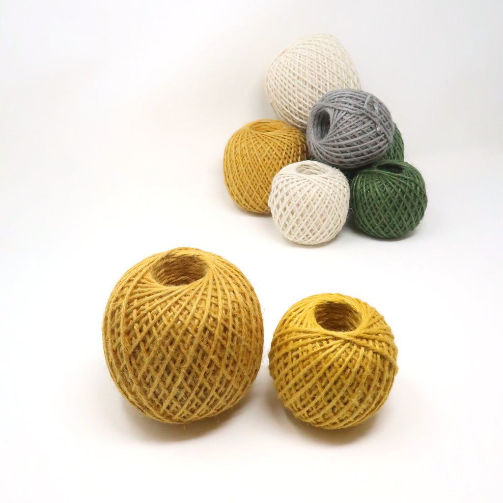 Balls of coloured jute twine bundled up against a white background