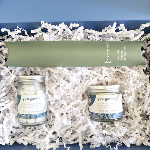 zero waste toiletry products in a blue box on abed of white crinkled paper 