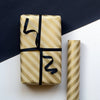 Gift box wrapped in gold striped paper with black ribbon on a white surface