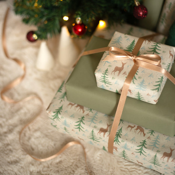 Wrapped Christmas presents with reindeer paper and gold ribbons under a Christmas tree.