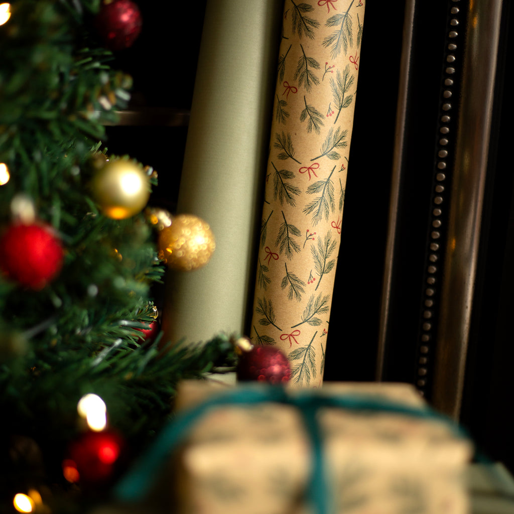 Decorative roll of paper with a floral pattern next to a Christmas tree with ornaments.