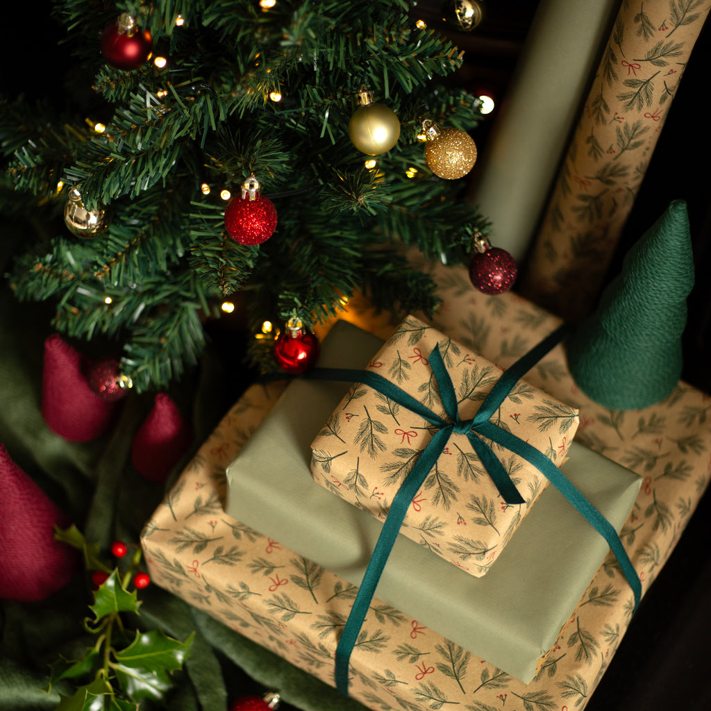 Gifts under a decorated Christmas tree with ribbons and ornaments.