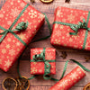 Red gift boxes with gold snowflake patterns and green ribbons on a wooden surface.