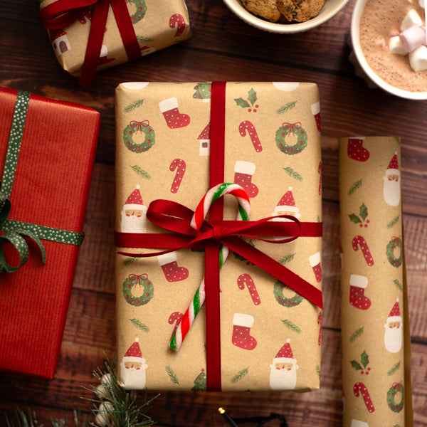 Christmas-themed gift wrap with red ribbon on a wooden surface.