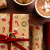 Christmas-themed gift box with a red ribbon, surrounded by hot chocolate and cookies on a wooden surface.