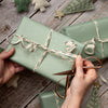Person curling a ribbon on a wrapped gift with decorative stars in the background