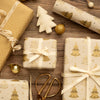 Decorative Christmas gift boxes with gold tree patterns on a wooden surface.
