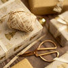 Decorative gift wrap with a ball of ribbon and scissors on a wooden surface
