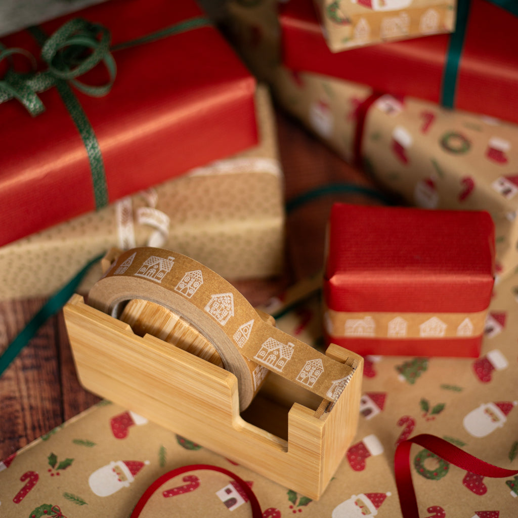 Wooden tape dispenser with decorative tape on a background of wrapped Christmas presents.