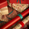 Gift wrap with red ribbon and patterned paper on a wooden surface