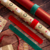 Rolls of Christmas-themed wrapping paper, sealing strips and ribbons on a wooden surface