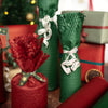 Close-up of wrapped presents with red and green honeycomb paper, ribbons, and a blurred festive background.