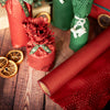 Red and green gift wrap on a wooden surface with decorative elements.