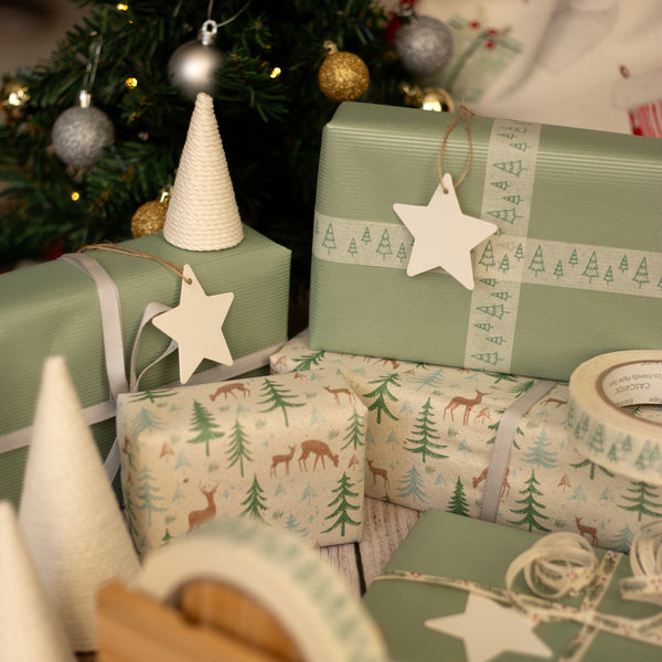 Green Christmas presents with festive patterns, star tags and decorations on a wooden surface.
