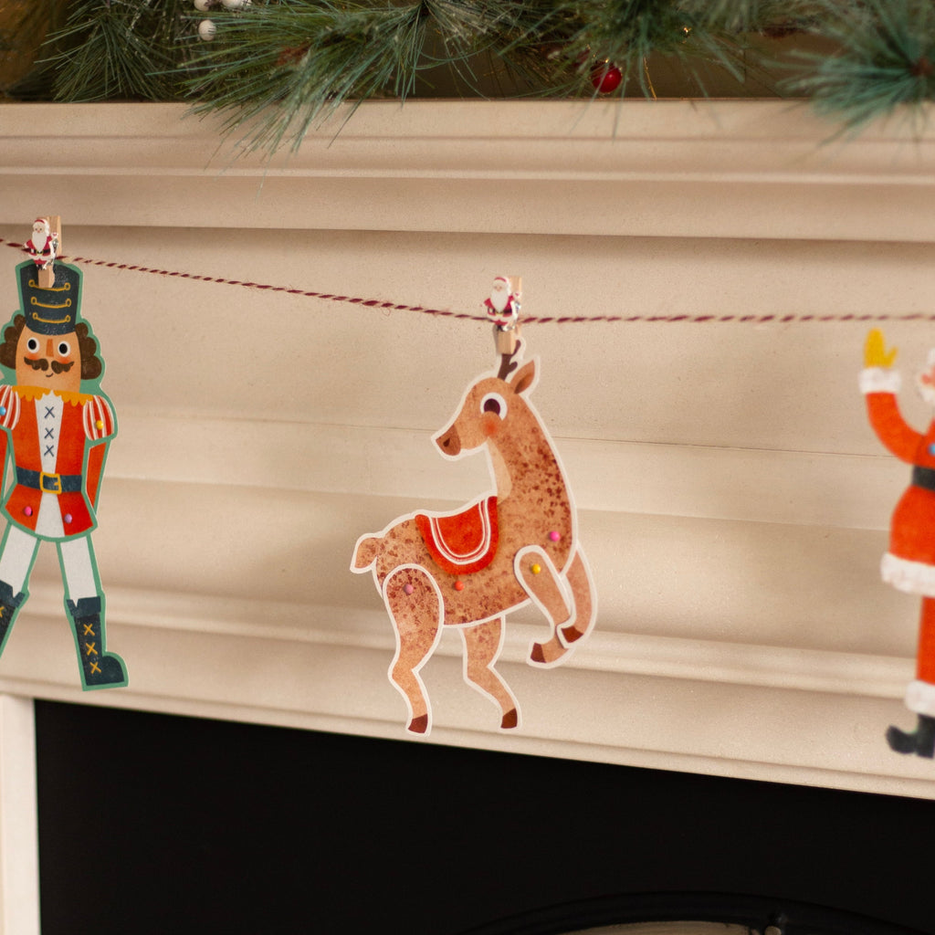 Decorative Christmas garland with a reindeer, nutcracker, and Santa Claus figure on a fireplace.