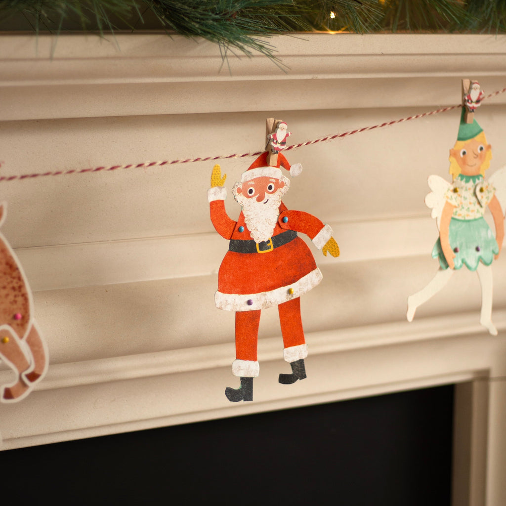 Decorative Christmas banner with Santa Claus, reindeer, and fairy on a fireplace mantle.