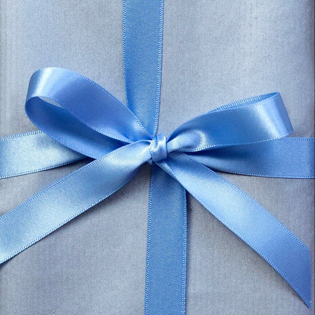 Silver gift box with blue ribbon on a light gray surface