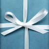 Blue gift box with a white ribbon on a beige and white background