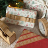 Gift wrap with gingerbread design, tape, and decorative items on a textured surface.