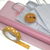Pink wrapping paper, silver gift bag, and yellow tape with heart designs on a white background
