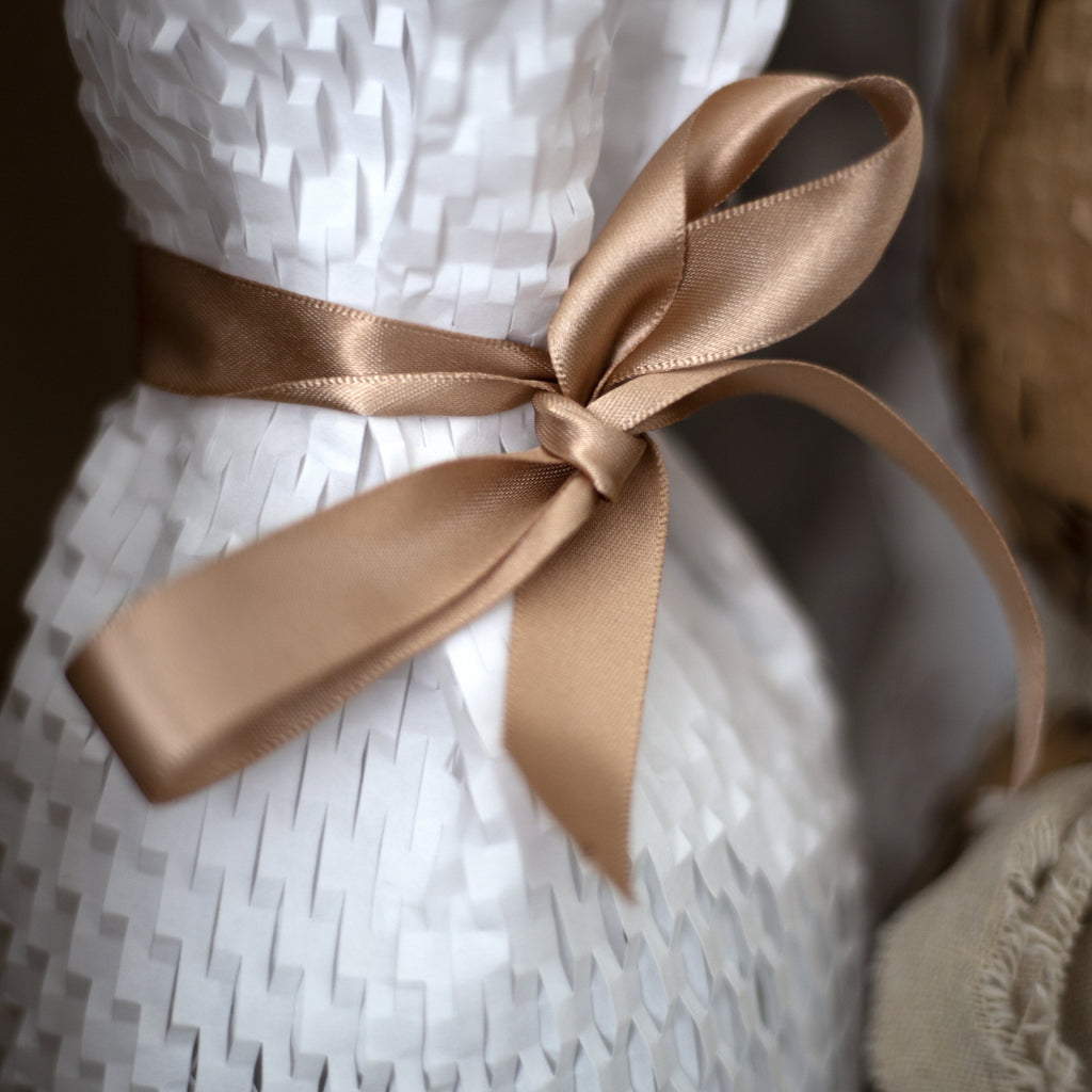 gold ribbon wrapped around white honeycomb paper