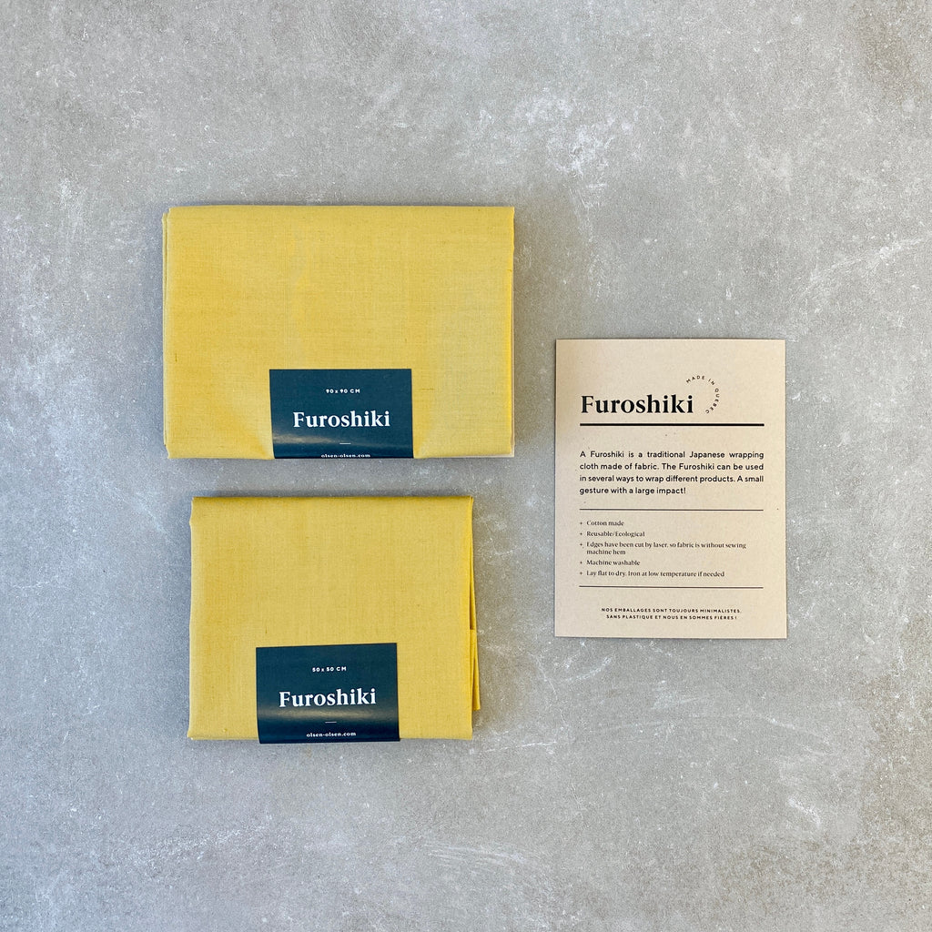 yellow folded furoshiki material gift wrap on a grey table