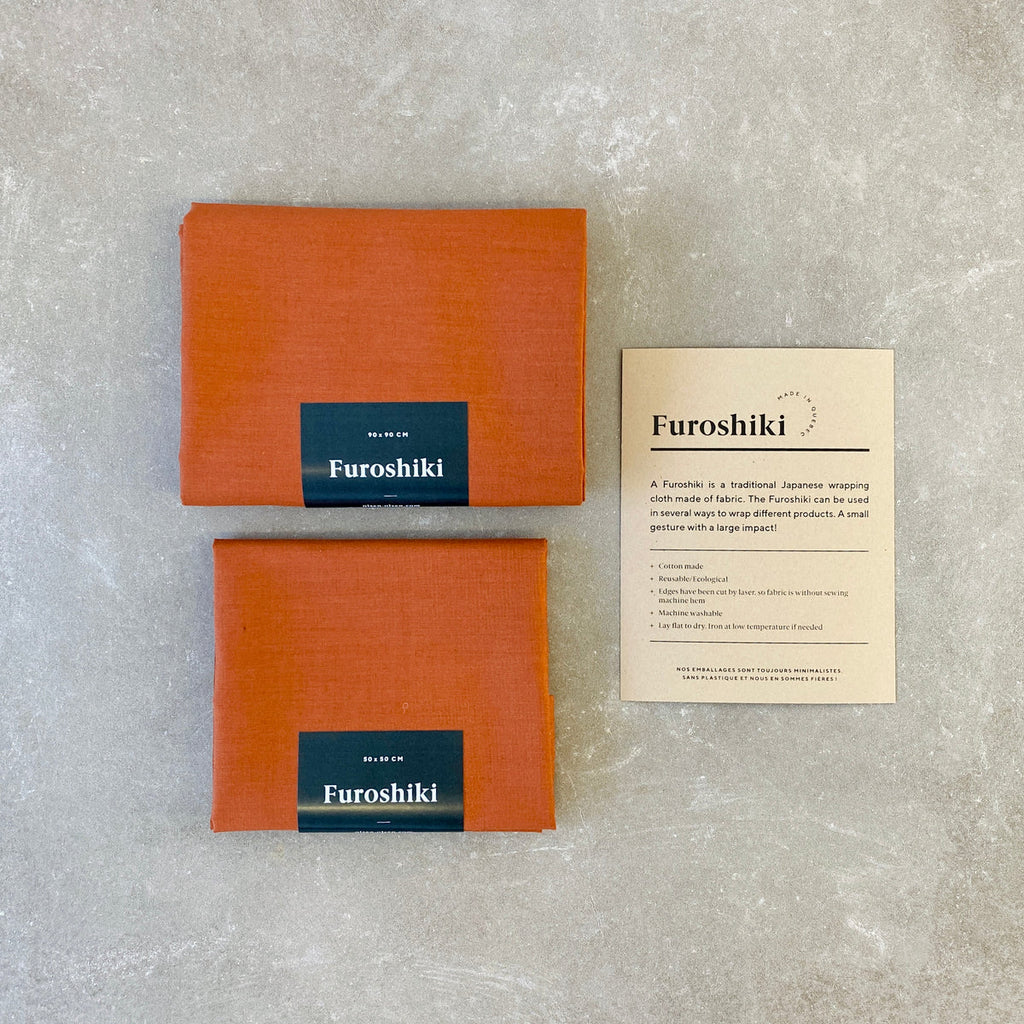 orange folded furoshiki material gift wrap on a grey table