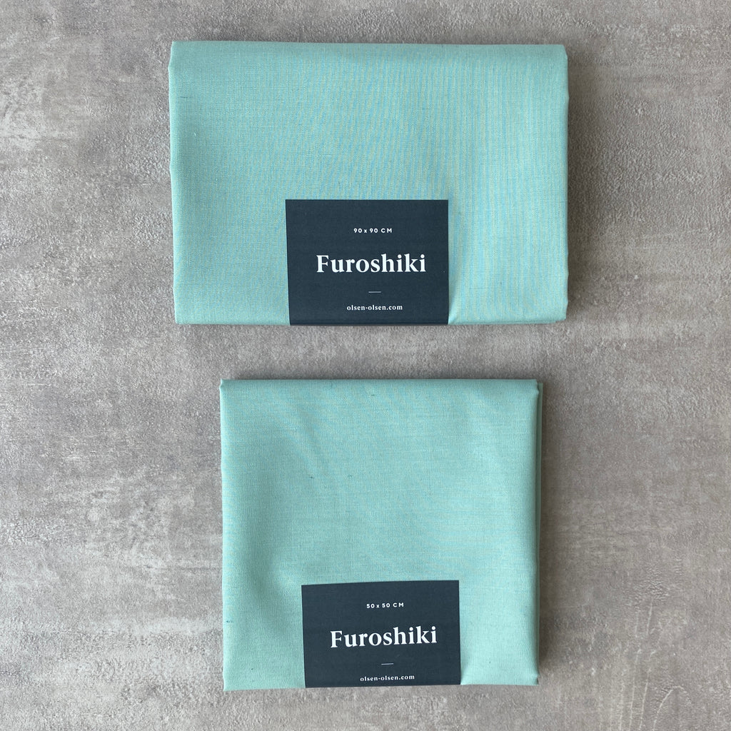 green folded furoshiki material gift wrap on a grey table