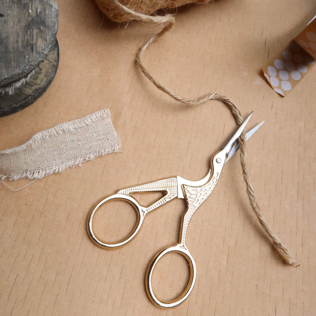 gold scissors cutting jute string on a brown table top