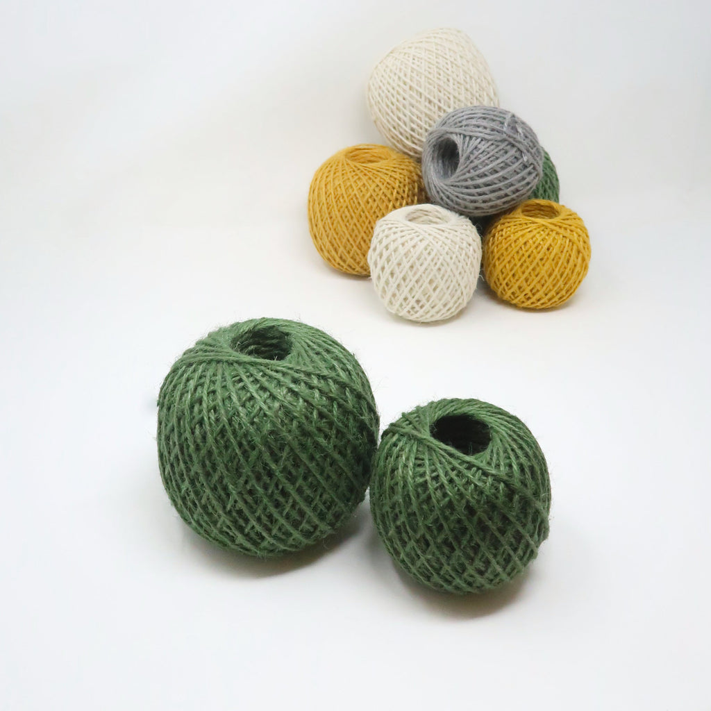 Balls of coloured jute twine bundled up against a white background