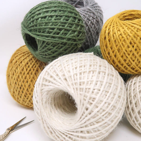 Balls of coloured jute twine bundled up against a white background