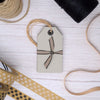 grey paper tags tied up in ribbon next to paper tape and jute string