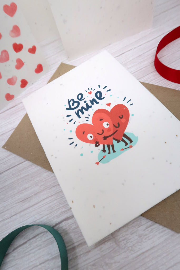 valentine card that says be mine with two cartoon love hearts hugging