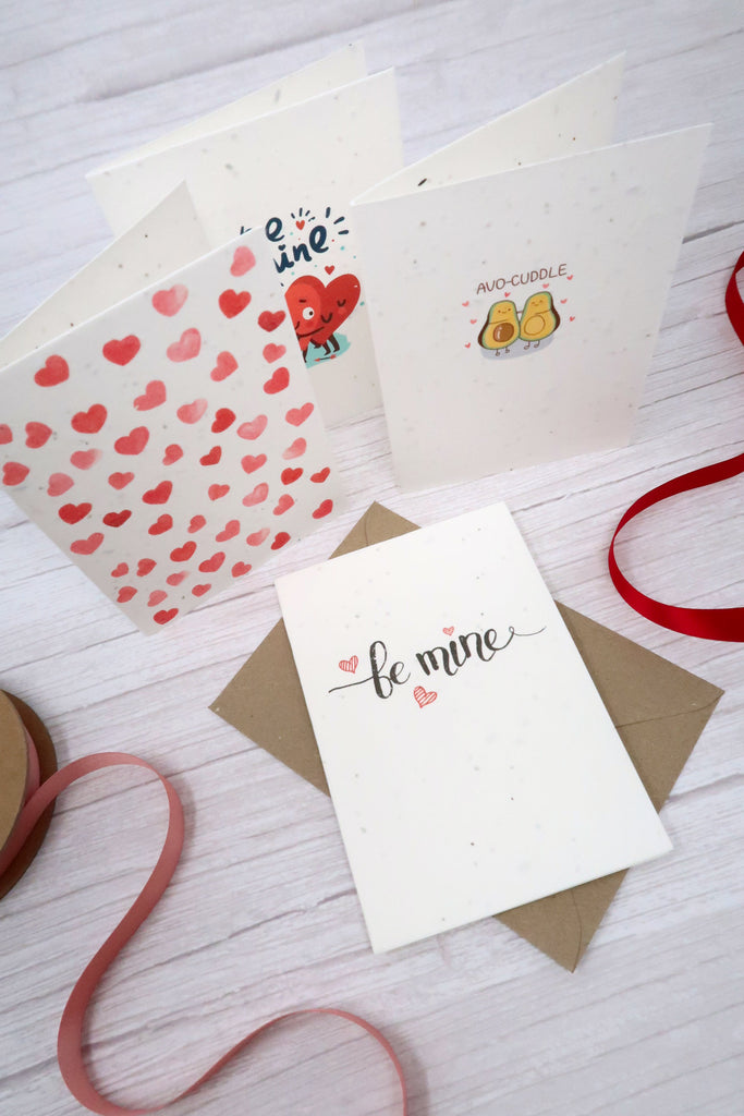 valentines cards on a white wood table with red ribbon and brown envelopes